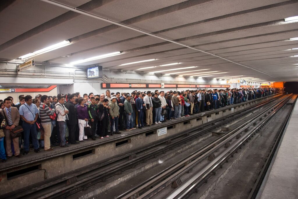 Rush hour on the Mexico City metro with hundreds of people waiting on a platform.