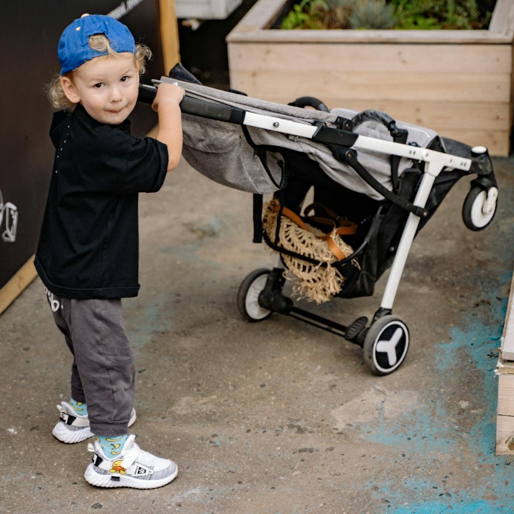 A young child plays with a stroller outdoors, showcasing childhood innocence and playfulness.